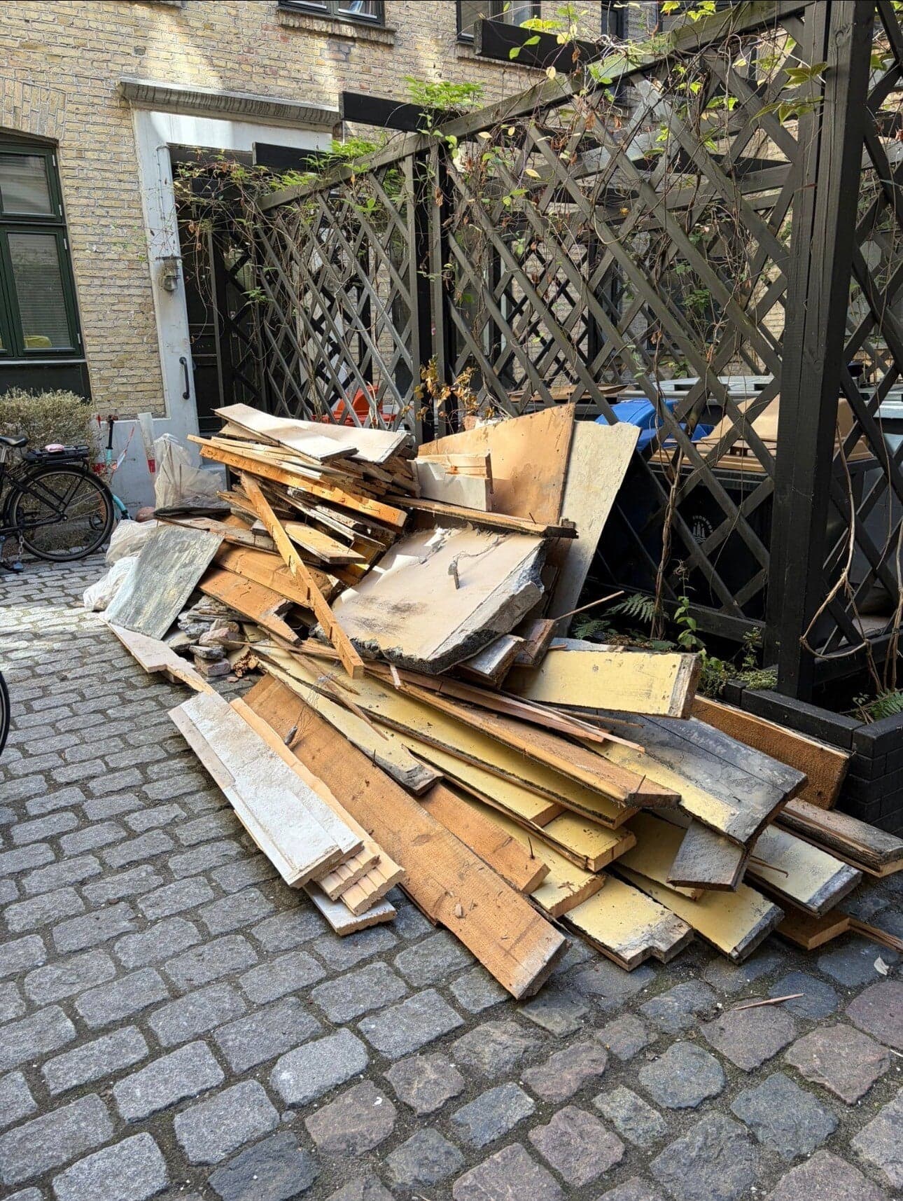 Træ og plader fra en renovering, samlet i en baggård