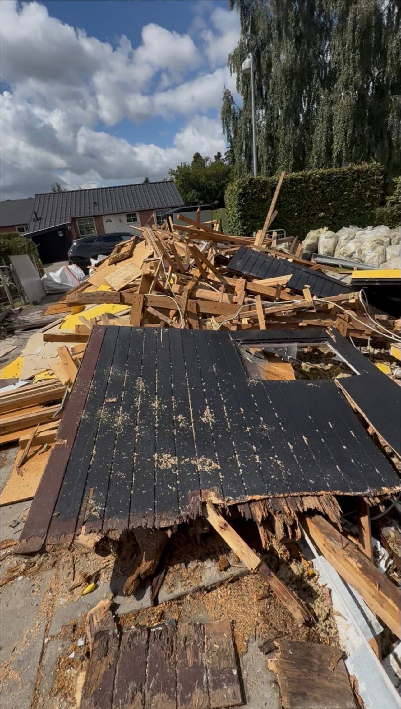 Nedrevet træskur og byggeaffald i en indkørsel